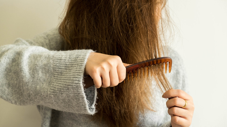 Woman combing damaged hair