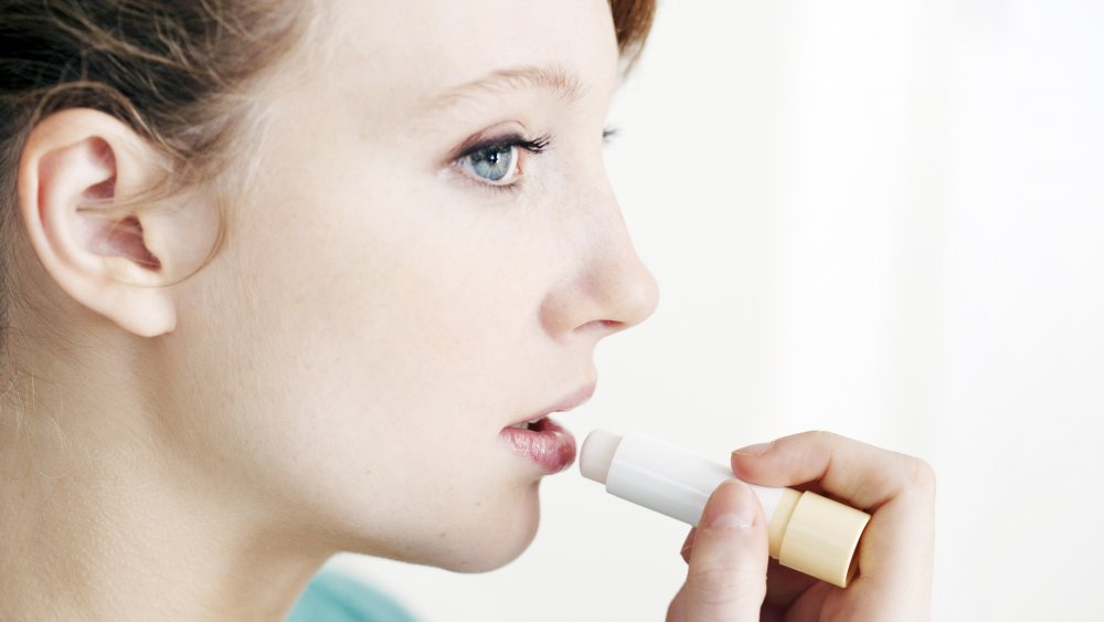 Woman applying chapped lip treatment