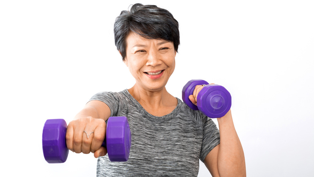 Older woman using purple dumbbells