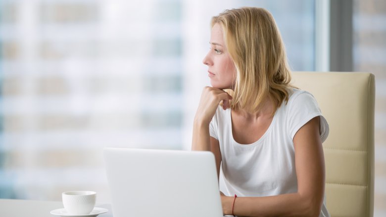 Woman looking away from computer and procrastinating