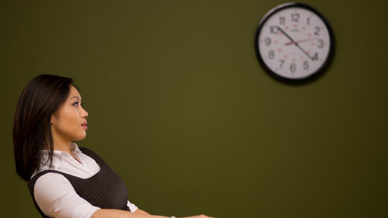 Woman watching the clock and procrastinating