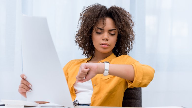 Woman checking her watch and procrastinating