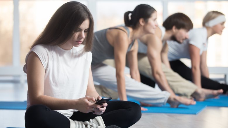 Woman procrastinating at yoga class