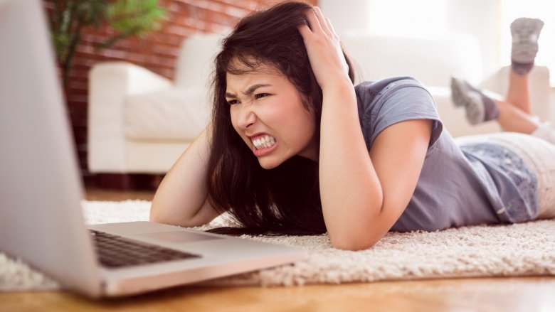 woman looking angrily at laptop