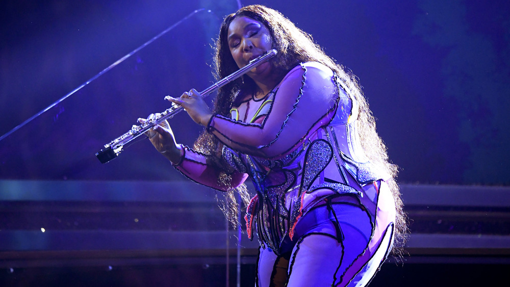 Lizzo performing onstage with her flute
