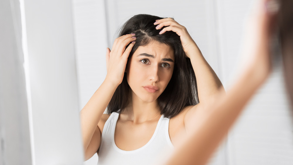 Woman studying scalp in mirror.