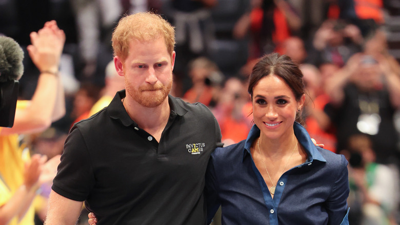 Prince Harry frowning next to Meghan Markle