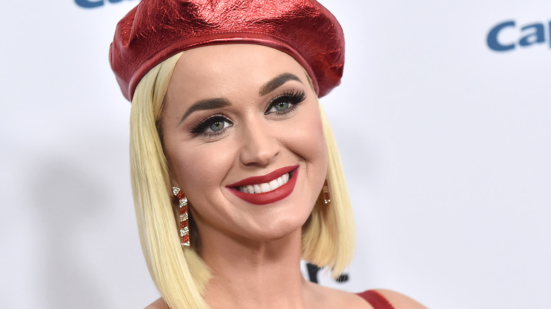 Katy Perry smiling in a red cap