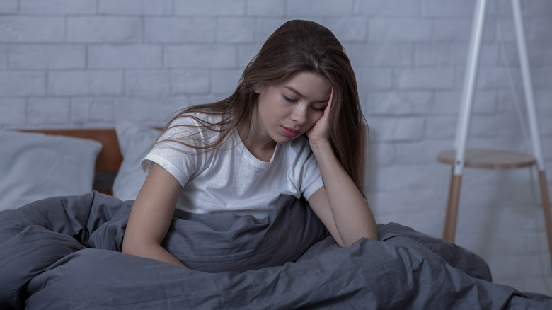 Woman sitting in bed, struggling with seasonal depression