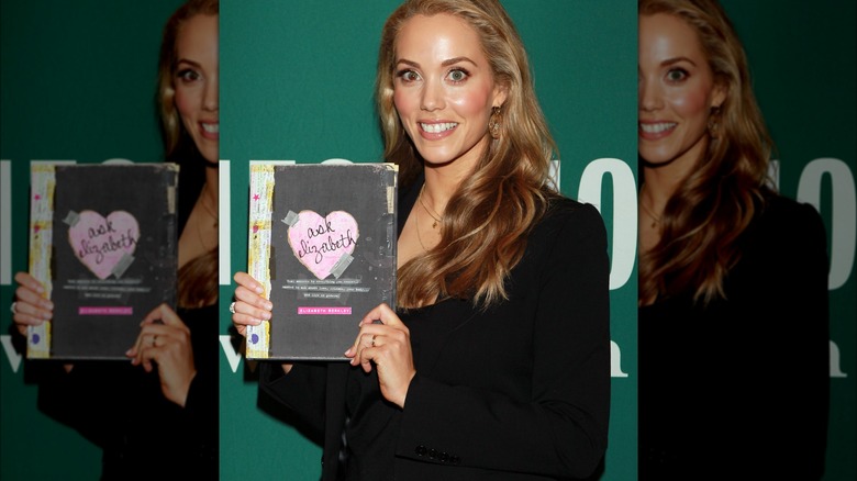 Elizabeth Berkley holding a book and smiling