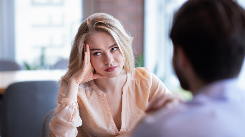 Woman uninterested sitting opposite man