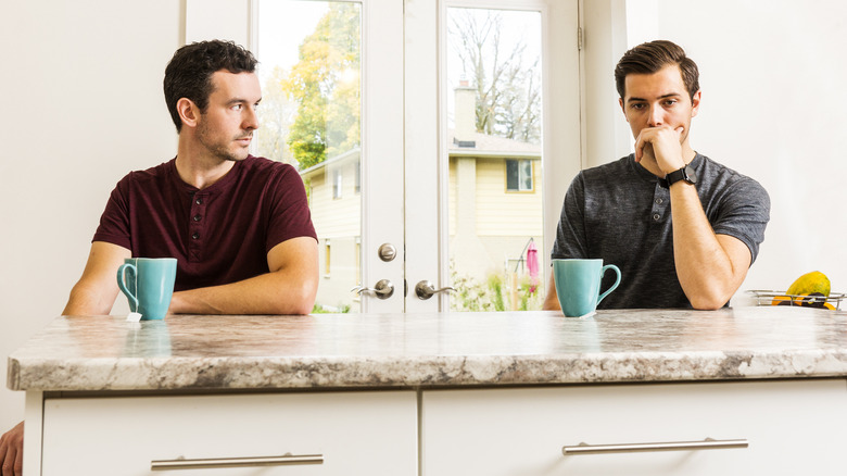 Two men sitting apart at kitchen counter