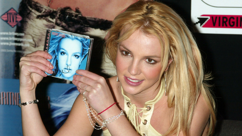 Britney Spears smiling holding up signed copy of "In the Zone"