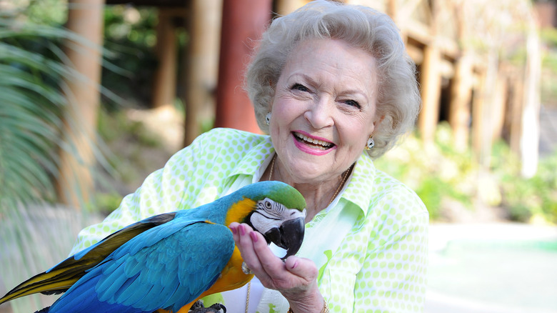 Betty White smiling with a parrot