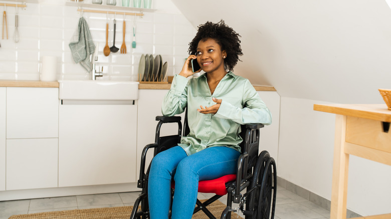 Woman in wheelchair speaking on his phone in kitchen