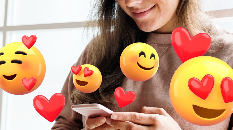 Closeup of woman's lower face holding phone surrounded by emoji graphics