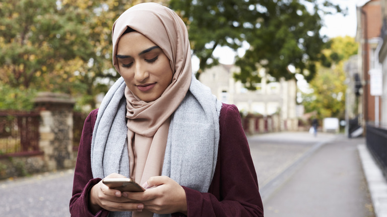 Woman looking at phone while walking outside