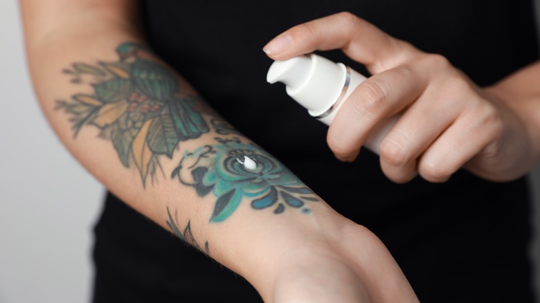 hand squirting lotion onto tattooed arm