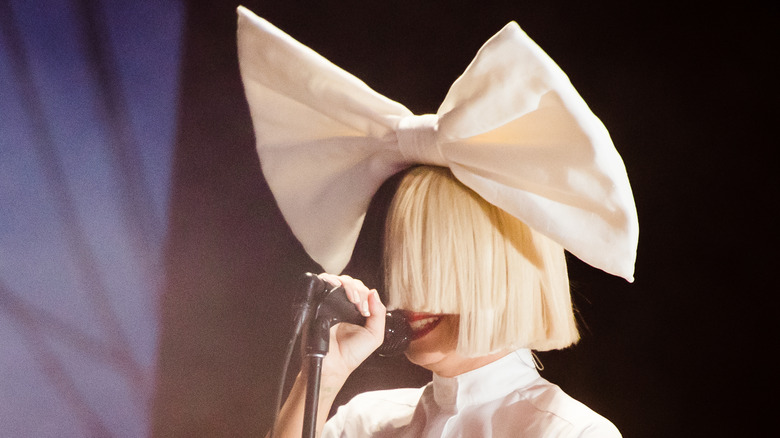 Sia performing with a wig