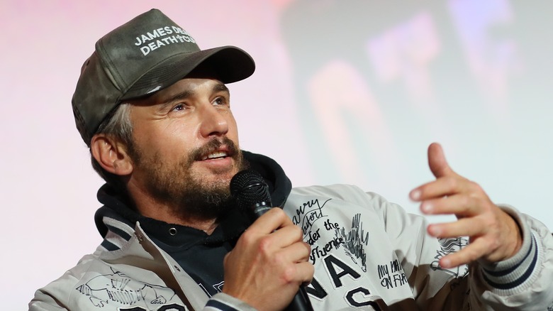 James Franco speaking onstage in a baseball cap