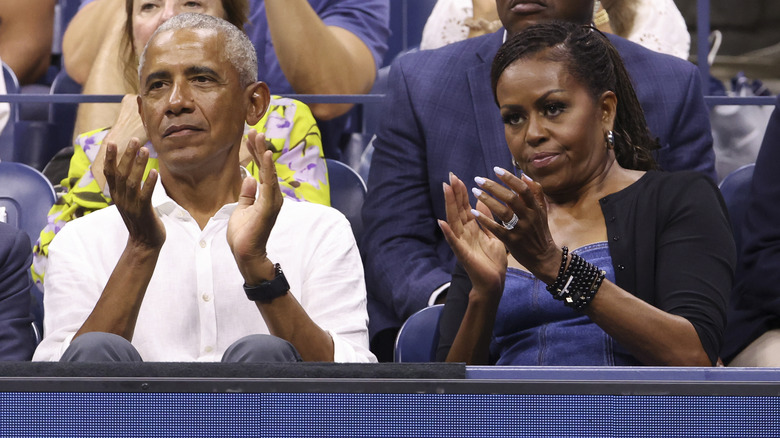 Barack and Michelle Obama sitting in bleachers clapping