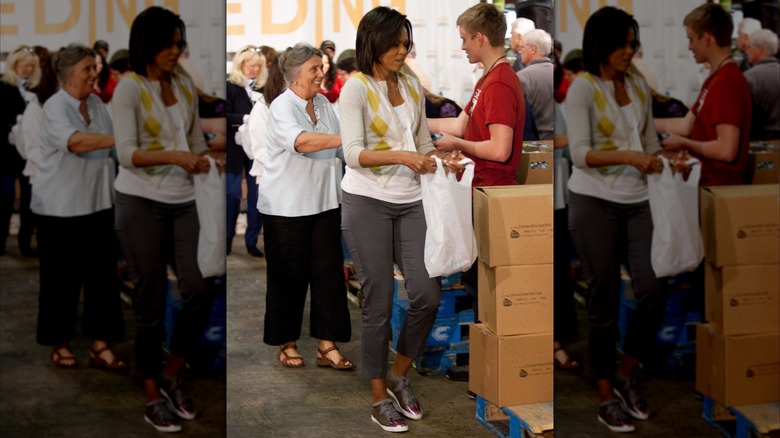 Michelle Obama holding a plastic bag while volunteering at a food bank