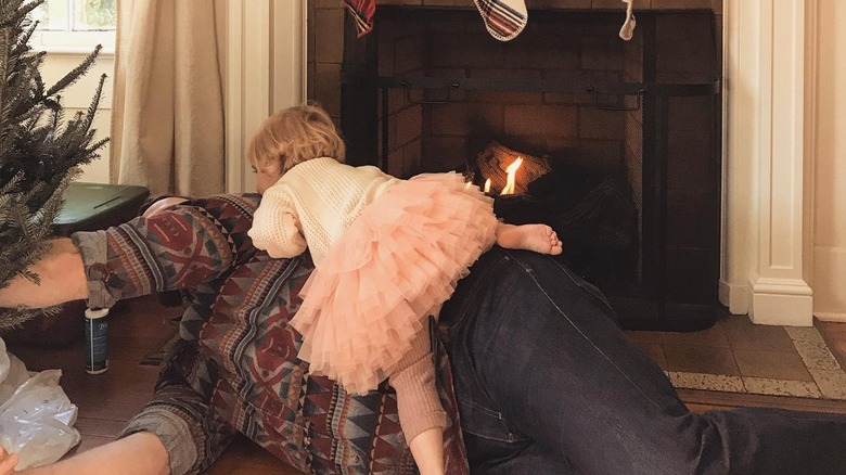 One of Ben's daughters sits on him while he decorates