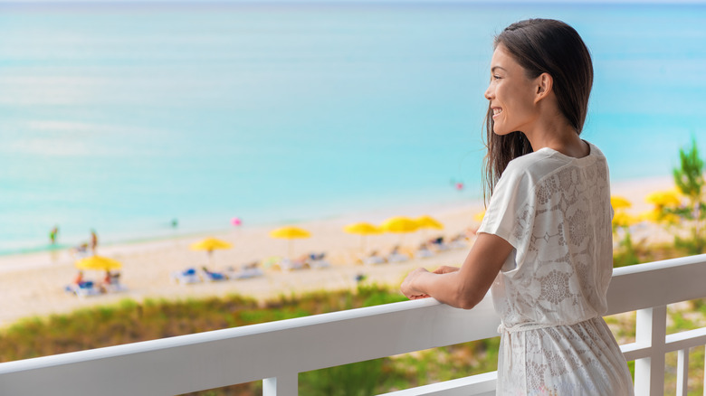 woman standing on her balcony looking at the beach