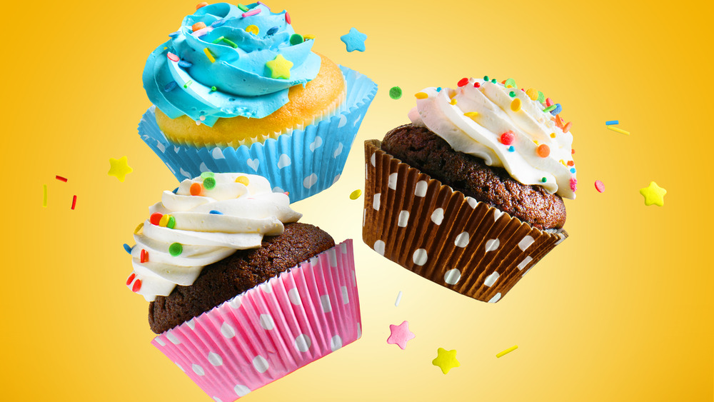 An assortment of cupcakes is surrounded by sprinkles