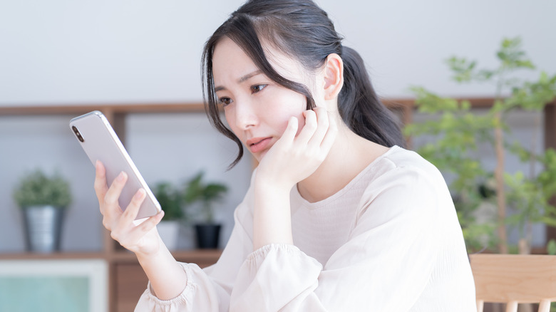 Woman looking unhappily at phone