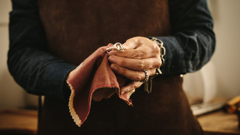 woman polishing jewelry with cloth