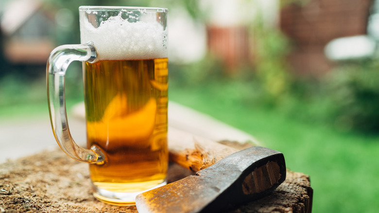 beer glass on wood next to axe