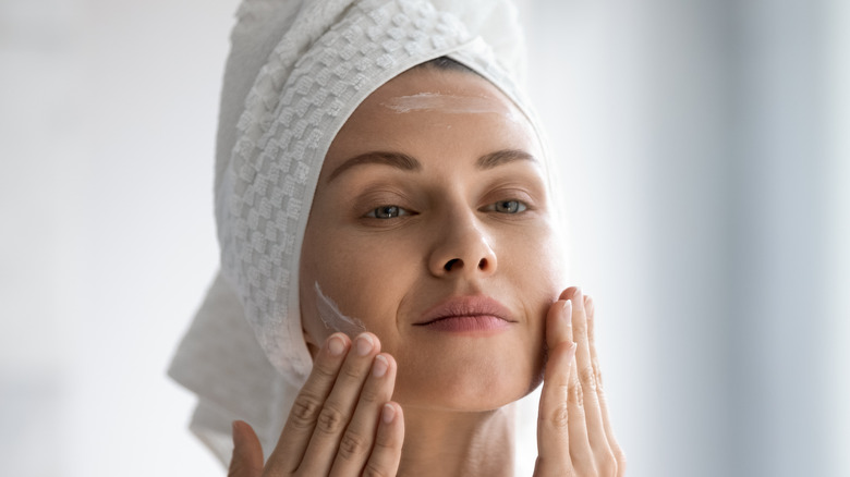 Woman applying skin product after showering