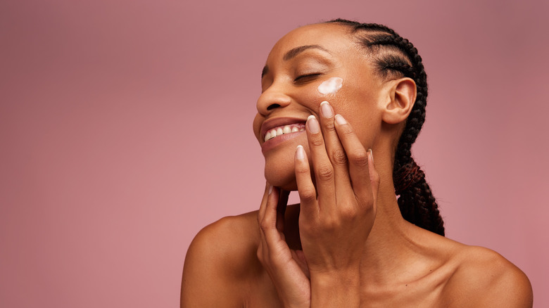 Woman applying moisturizer to face