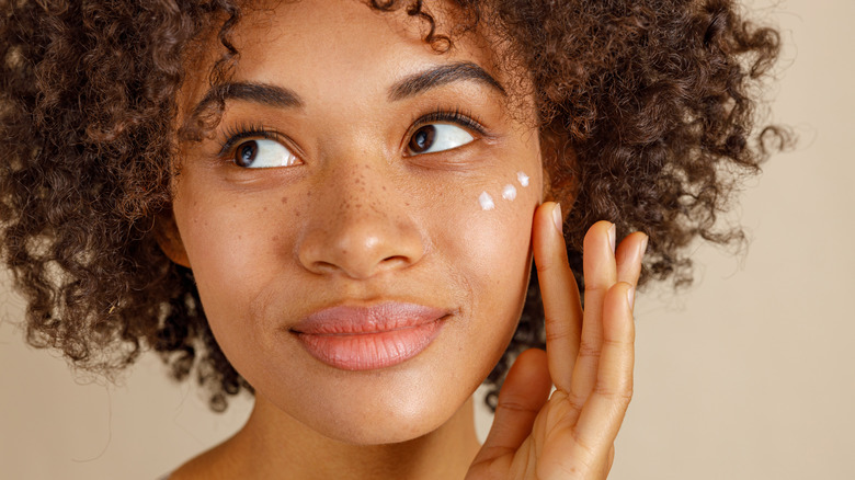 Woman putting cream on her face