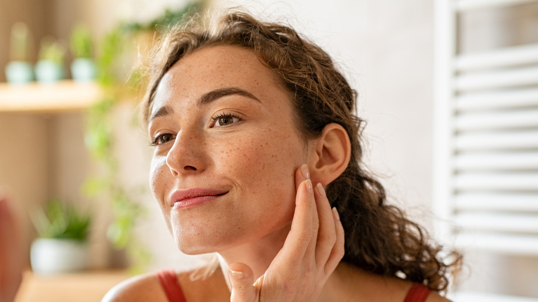 Woman looking at face in mirror