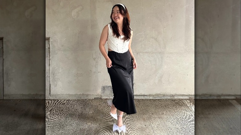 Person in black skirt smiling in hallway