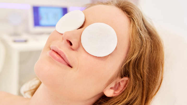 A woman with cotton pads over her eyes