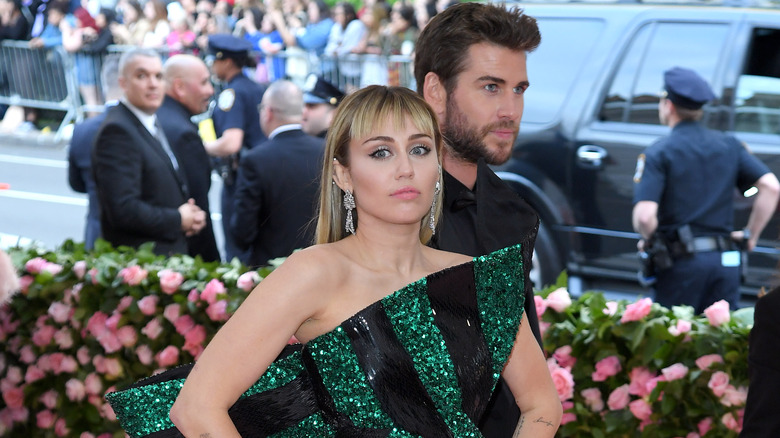 Miley Cyrus posing in front of Liam Hemsworth