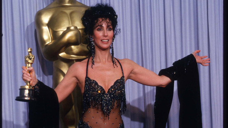 Cher arms outstretched holding her Oscar