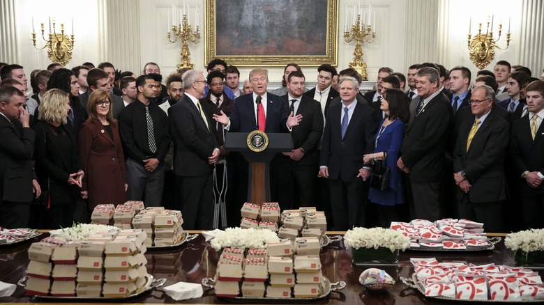 President Donald Trump behind a table full of McDonald's hamburgers and Chick fil-a sandwiches on March 4, 2019 in the Diplomatic Room of the White House