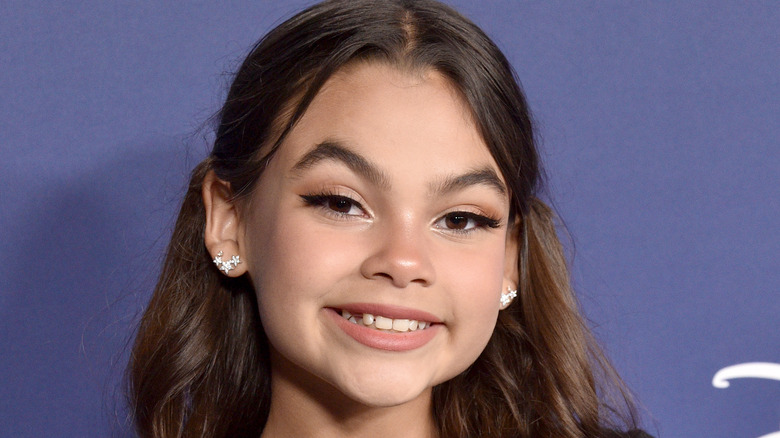 Ariana Greenblatt smiling on a purple background