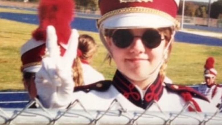 Ashley McBryde giving a peace sign while playing in a marching band