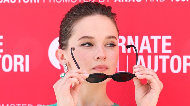 Cailee Spaeny putting on sunglasses