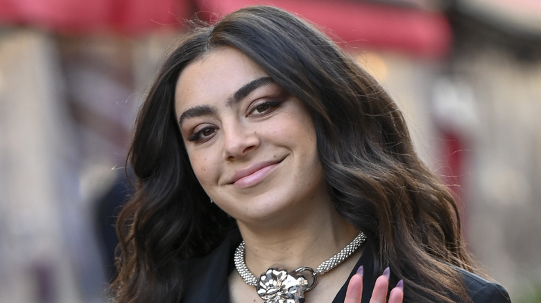 Charli XCX smiling and waving