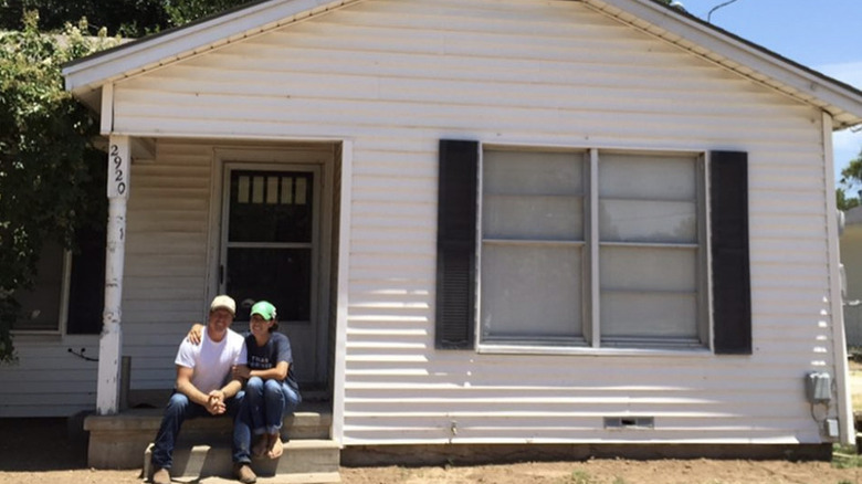 Chip and Joanna Gaines sitting on the front step of a house