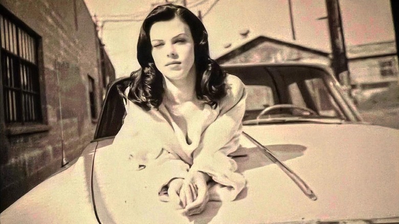 Debi Mazar lounging on a car