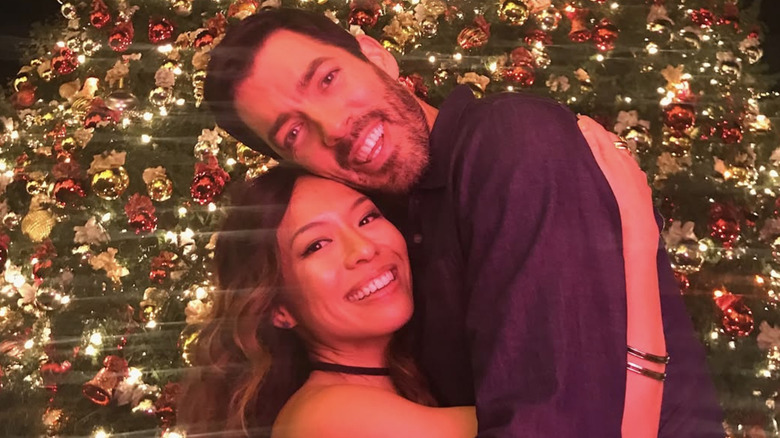 Linda Phan and Drew Scott hugging in front of a Christmas tree