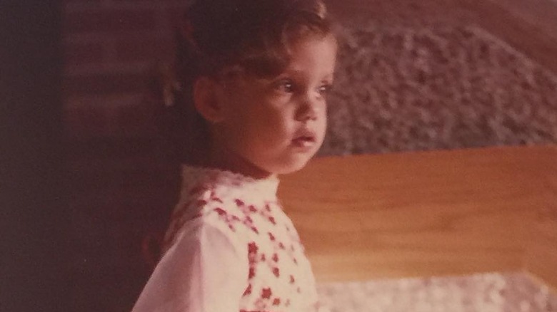 A childhood photo of Elizabeth Berkley holding flowers