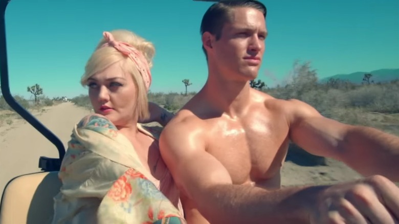 Elle King and shirtless man seated in music video